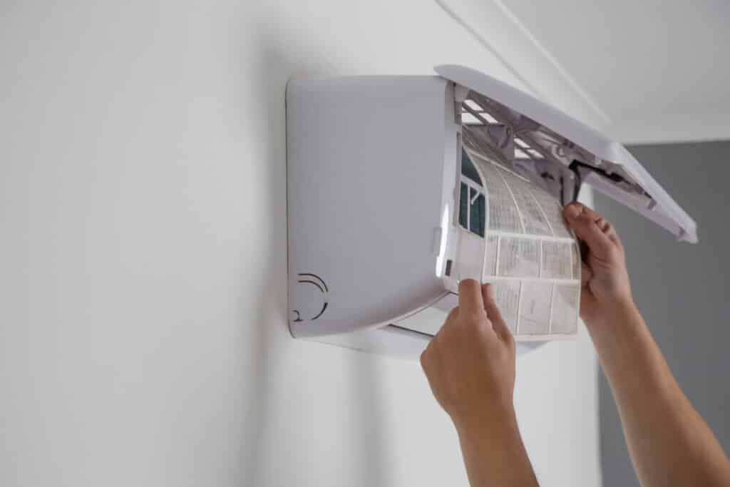Un technicien remplaçant le filtre d'un climatiseur mural lors d'une intervention de chauffage et climatisation.