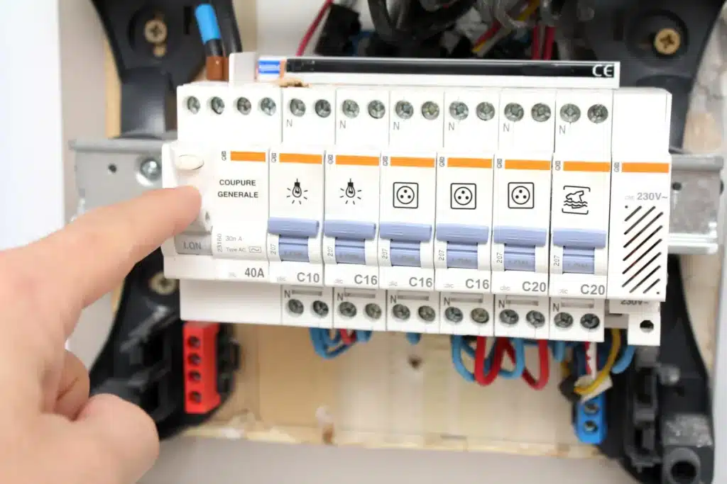 Un électricien manipulant des pinces pour réaliser un raccordement électrique dans un tableau de distribution.