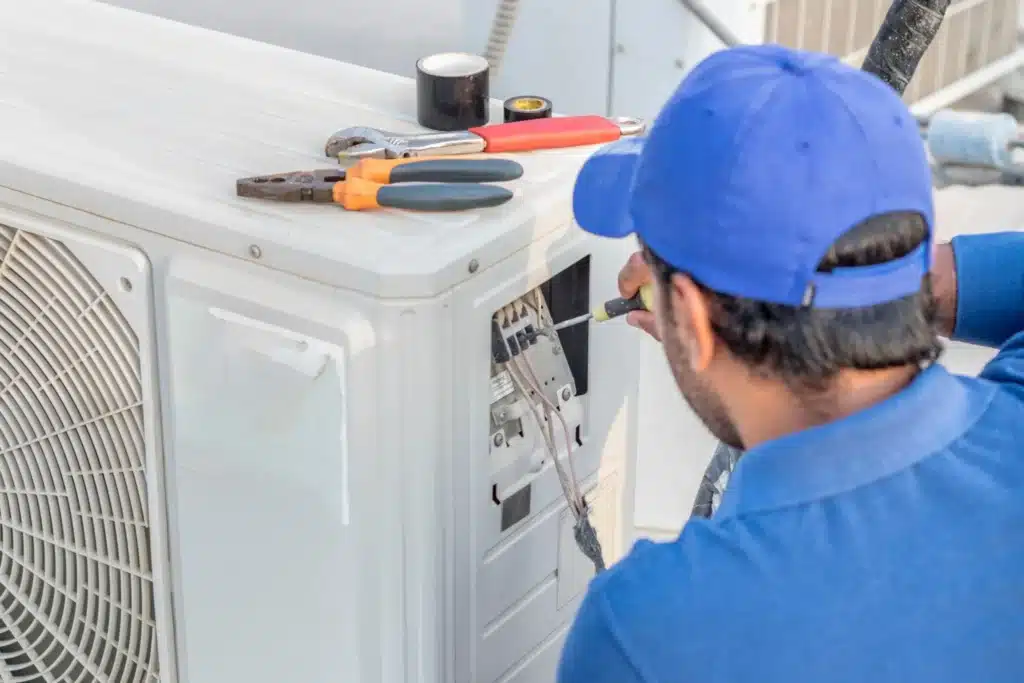 électricien installant une pompe à chaleur extérieure pour le chauffage