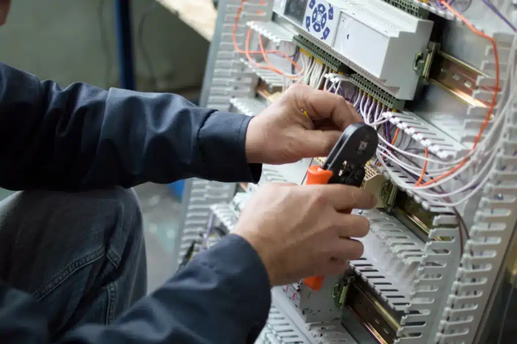 électricien travaillant sur un tableau électrique avec des outils professionnels
